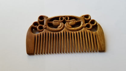 East Asian Phoenix Sandalwood Comb flat lay — low angle view highlighting pocket comb profile and depth of phoenix carving. this comb is made of single piece of wood. 
