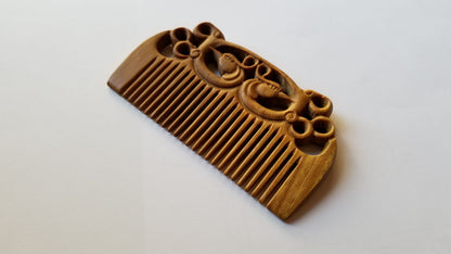 East Asian Phoenix Sandalwood Comb flat lay — top-down view of pocket-sized hand-carved sandalwood fine-tooth comb with phoenix motif. Comes with a gift bag. 