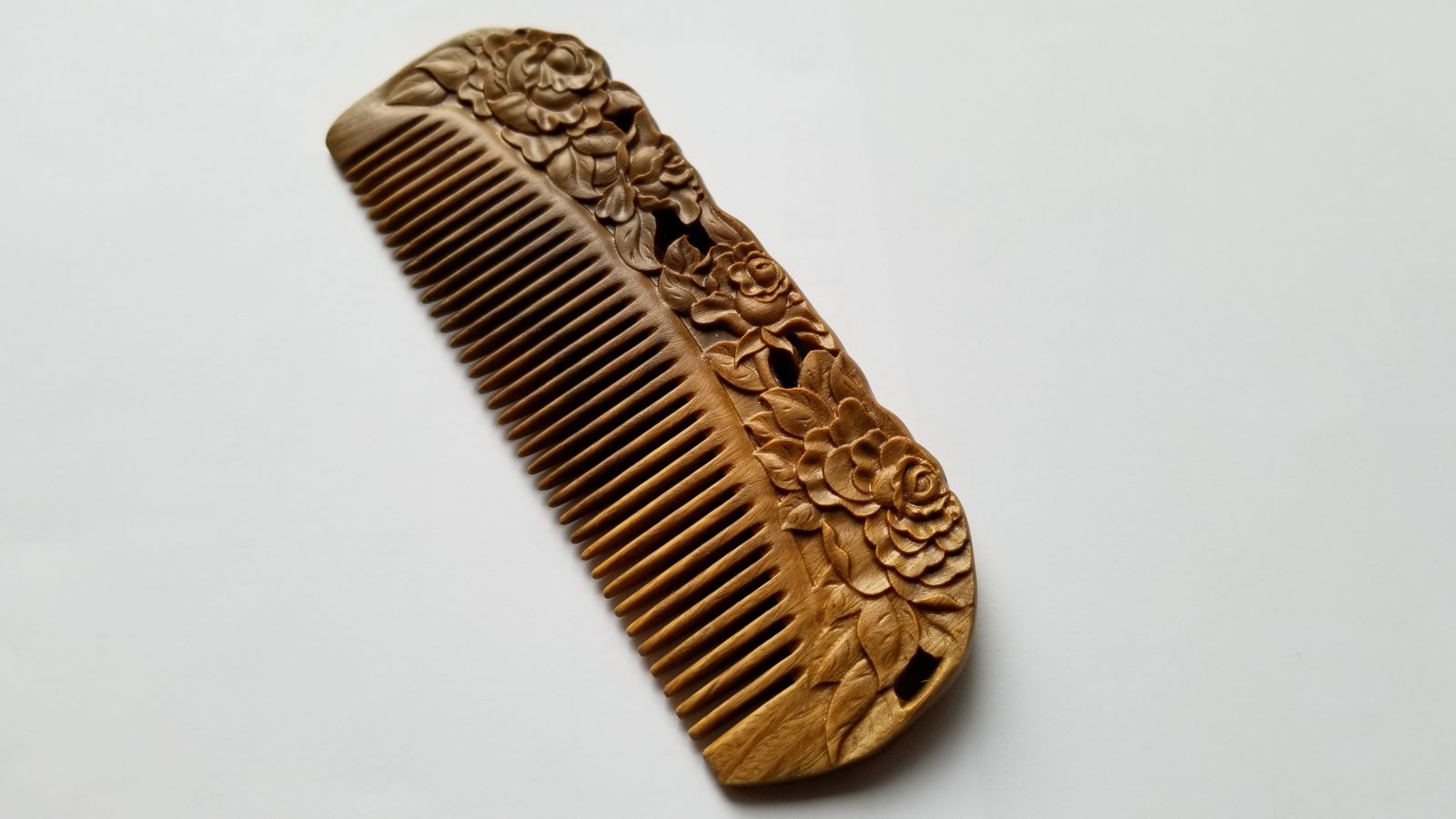 Rose Hand Carved Sandalwood Comb flat lay — top-down view of hand-carved sandalwood fine-tooth comb with blooming rose pattern