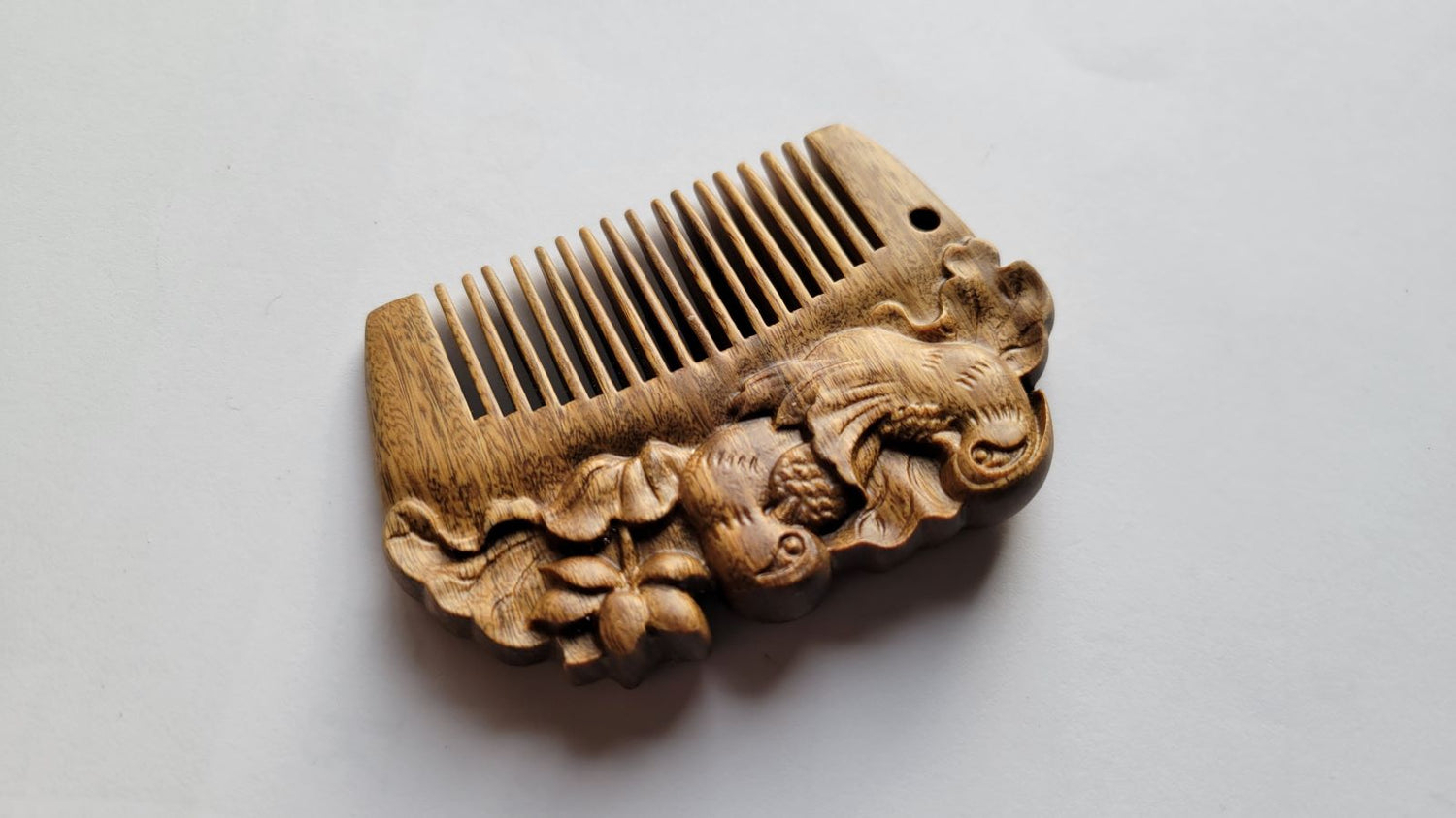 Close-up of mandarin duck carving on green sandalwood comb — hand carved detail, both sides