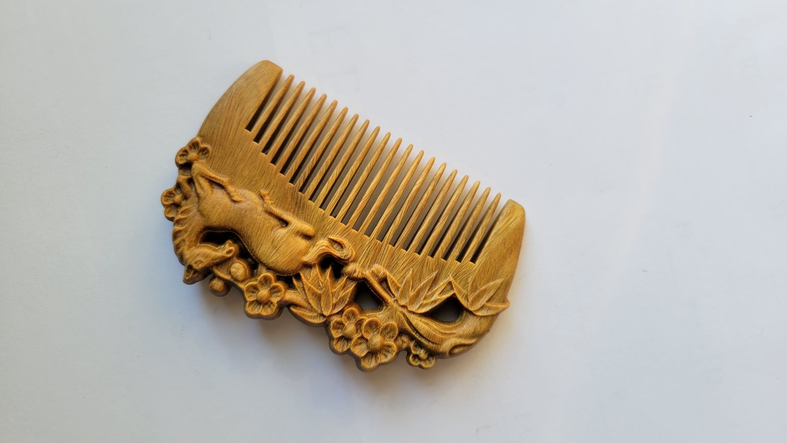 A light brown vintage style wooden comb with carving. The horse, bamboo and plums motif are on both sides of this comb. Comes with gift bag