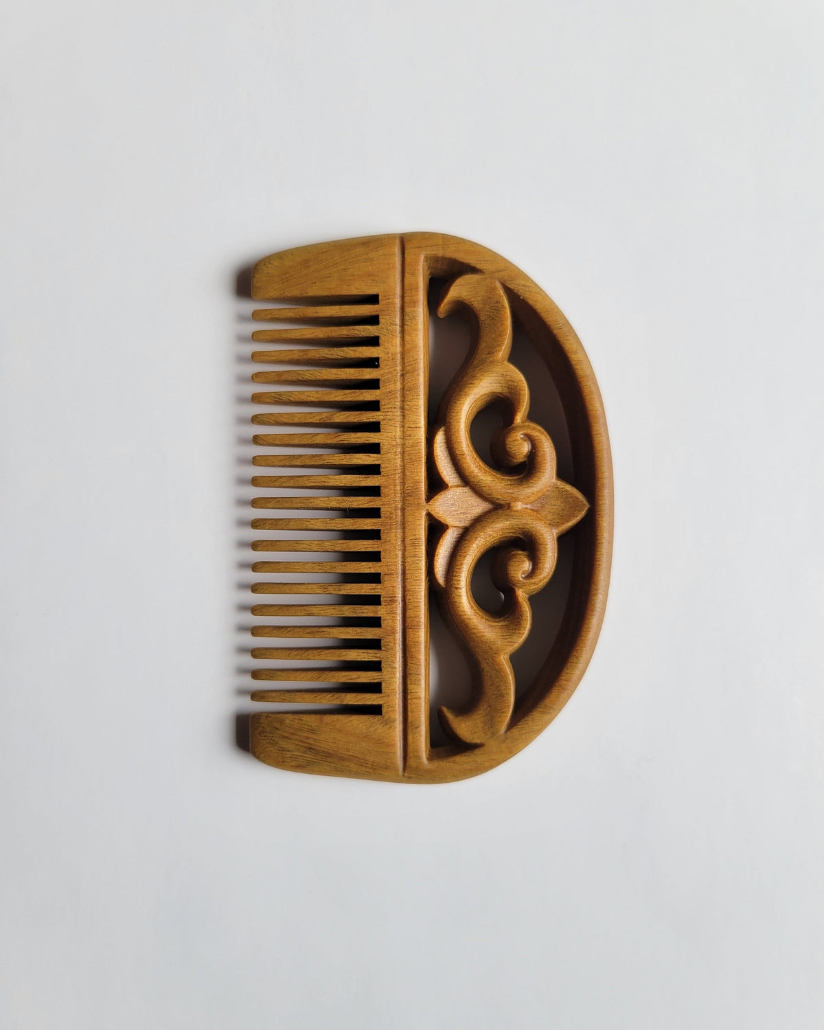 Green Sandalwood pocket comb overhead view — symmetric auspicious cloud pattern, 0.15 cm fine teeth spacing, detangling comb