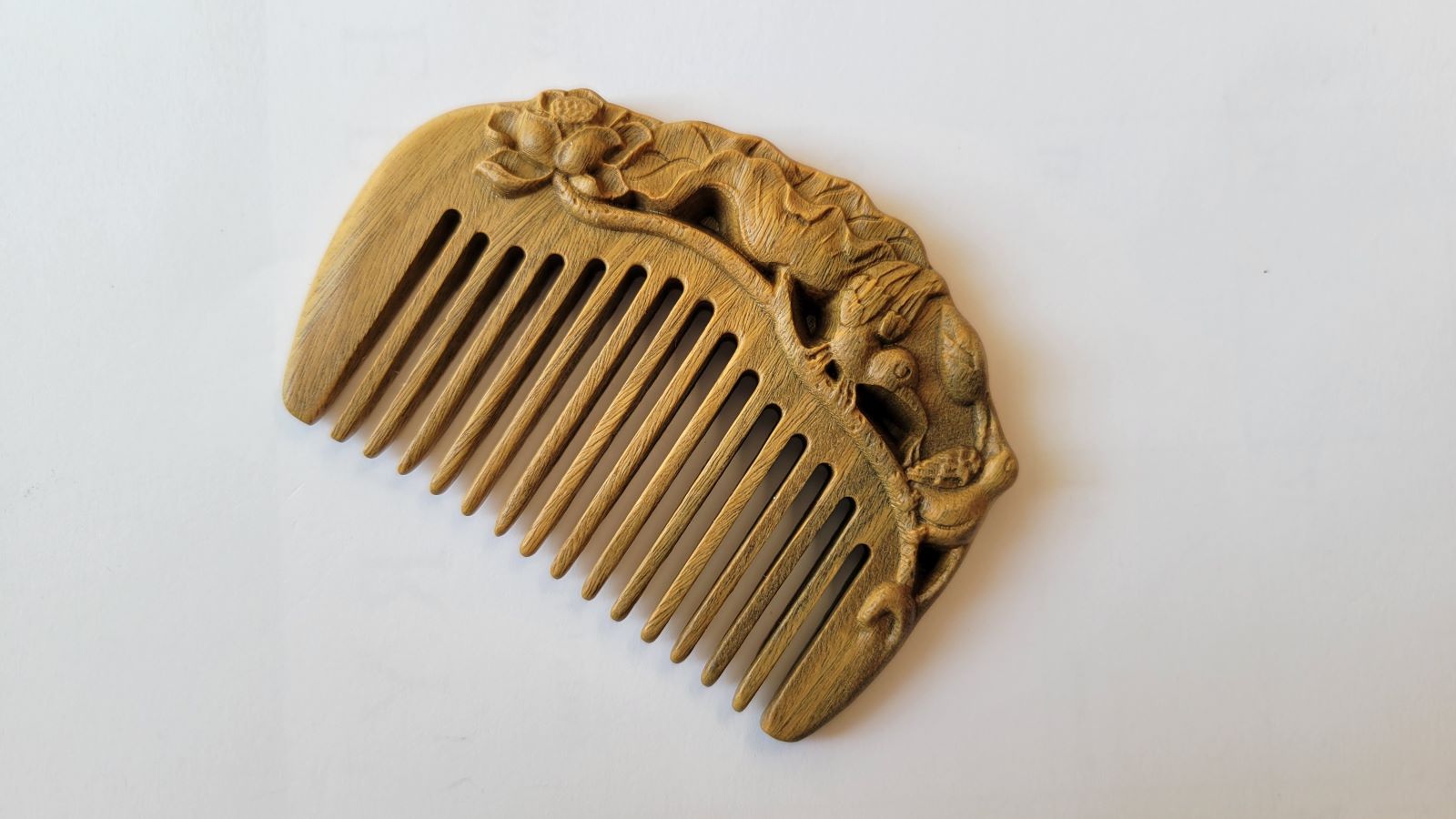 Green sandalwood mini comb angled view, hand-carved egret perched among lotus blooms, Yi Lu Lian Ke auspicious motif