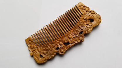 A wooden comb with intricate floral carvings. The comb is a warm brown color and features detailed carvings of flowers along the top edge. The teeth of the comb are evenly spaced and the overall design is elegant. comes with drawstring gift bag and gift for all occasion