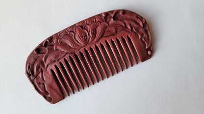 A carved wooden comb with a lotus flower design. Lotus flower The lotus is a sacred symbol associated with purity, awakening, transformation, and compassion. The comb is made of a smooth, polished purple heart wood.