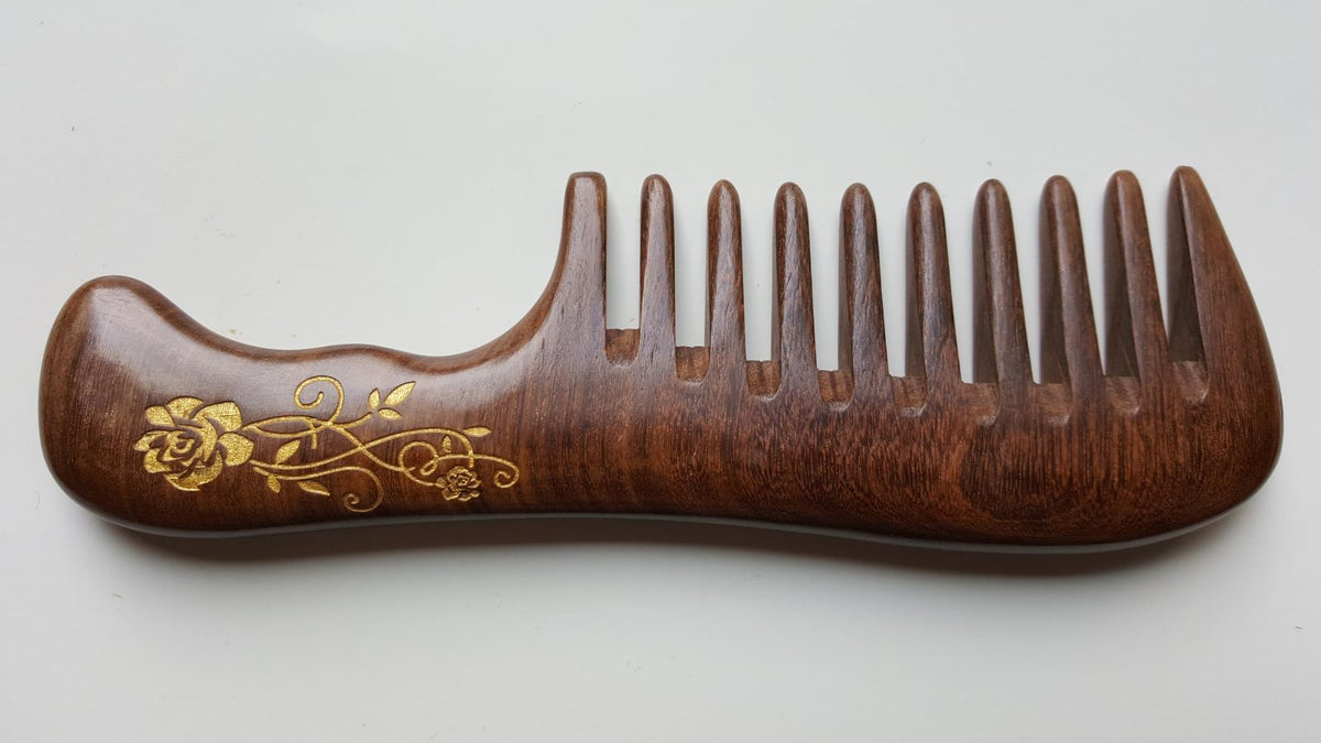 A brown wooden comb with a decorative gold floral design. The comb has a long ergonomic handle and a extra wide, rounded tooth.