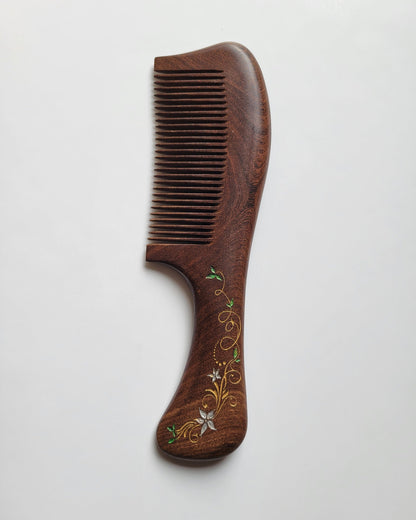 A dark brown wooden comb with a decorative floral design on the handle. The design features elegant ivy in gold, white and green. Great gift for her