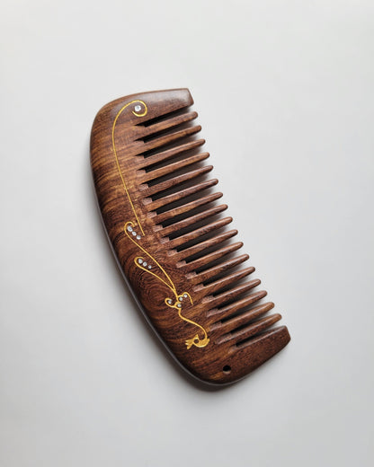 Wide tooth anti-static wood comb for curly, thick, and wavy hair, flat lay overhead view — Arakicrafts.  The design is on the handle and along the side.