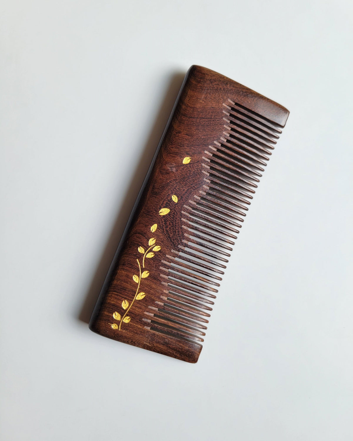Dark chocolate Sucupira wood grain comb — gold ivy leaf motif, overhead flat lay, fine tooth detangling