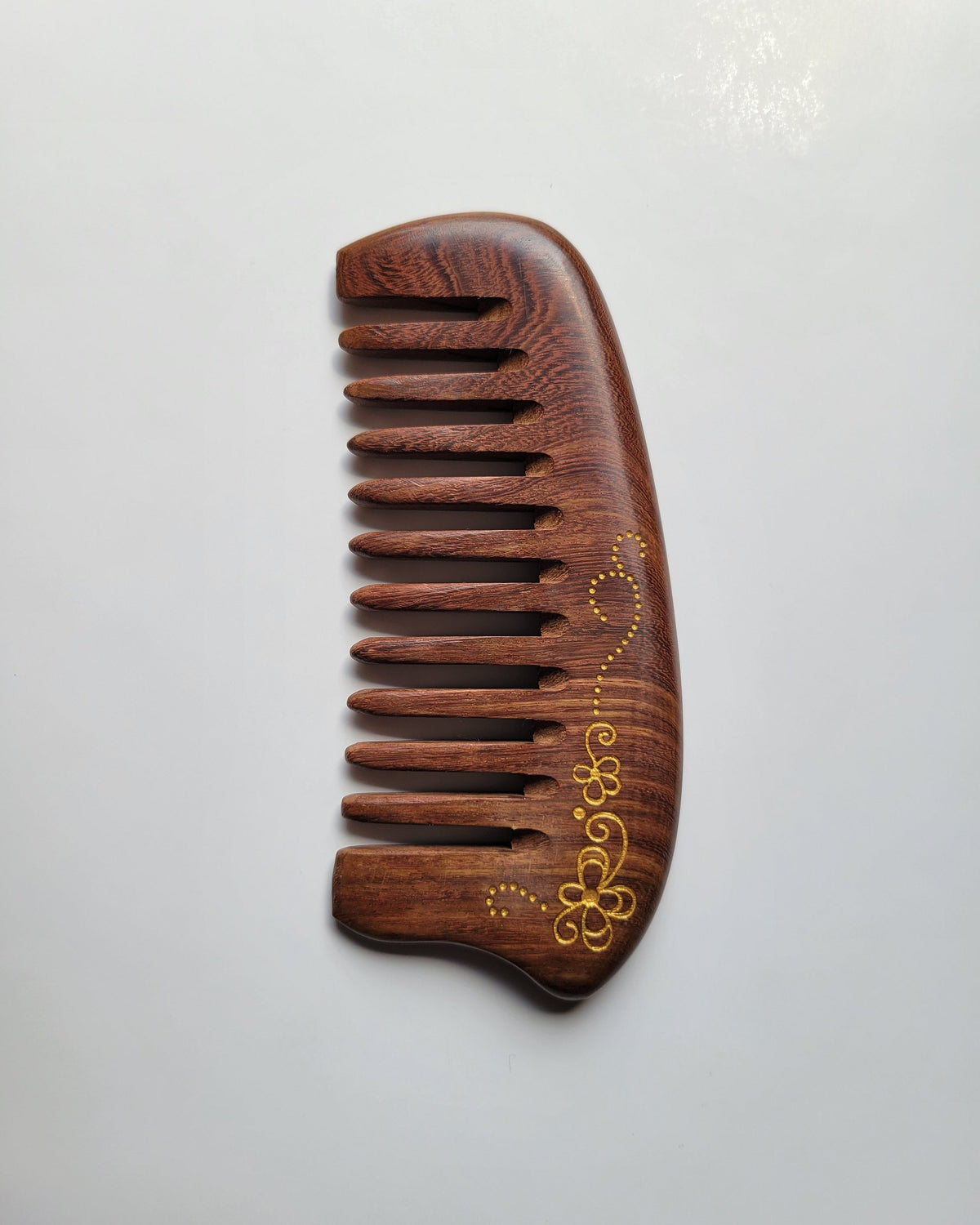 Hand-painted gold floral scroll Sucupira wood comb, wide teeth, two four-petal flowers with curling vine detail, dark hardwood hair comb