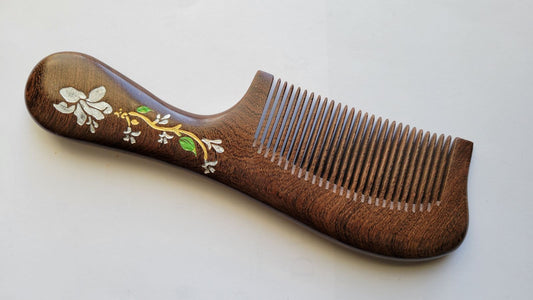 Hand painted magnolia flower wood comb in Sucupira hardwood, flat lay front view — Arakicrafts.  The design features white flowers, green leaves, and gold accents.