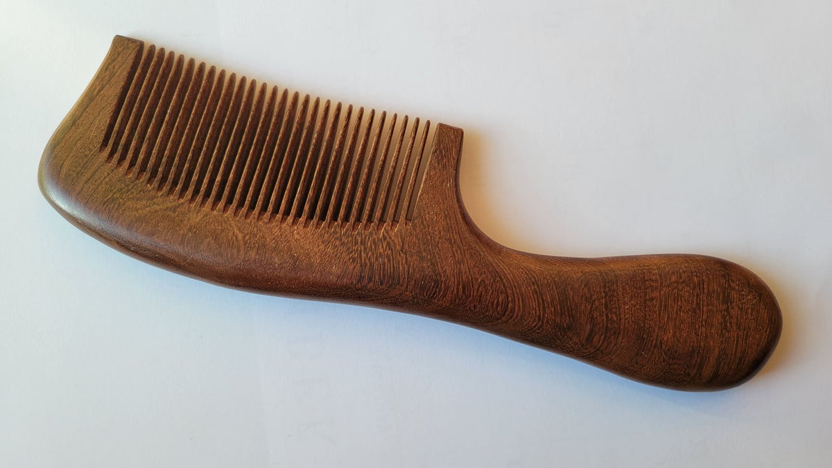 Sucupira wood comb back view showing natural reddish-brown grain texture, ergonomic rounded handle, durable South American hardwood