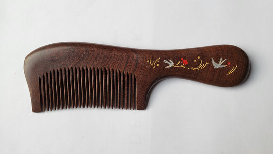  A wooden comb with a dark brown finish. The handle features an ornate design with silver swallow birds, red flowers, and gold accents. The comb's teeth are finely spaced, and the overall design is elegant.