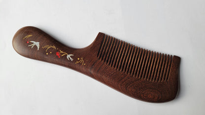 Close-up of silver swallow birds, red flowers, and gold accent detail hand painted on wood comb handle — Arakicrafts