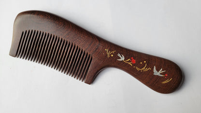 Handcrafted wood comb with swallow and floral motif, flat lay angled view showing single-piece hardwood grain — Arakicrafts