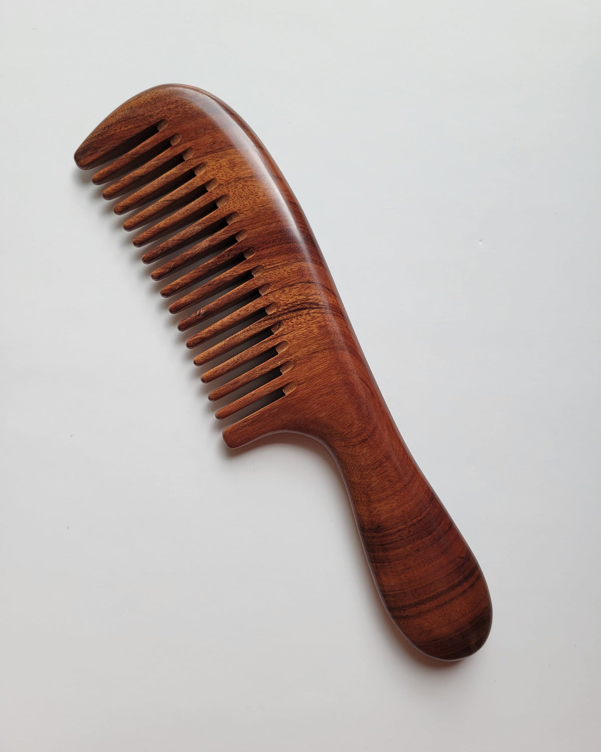 African Mopane wood comb for women — wide teeth, curved handle, warm-toned hardwood — Arakicrafts