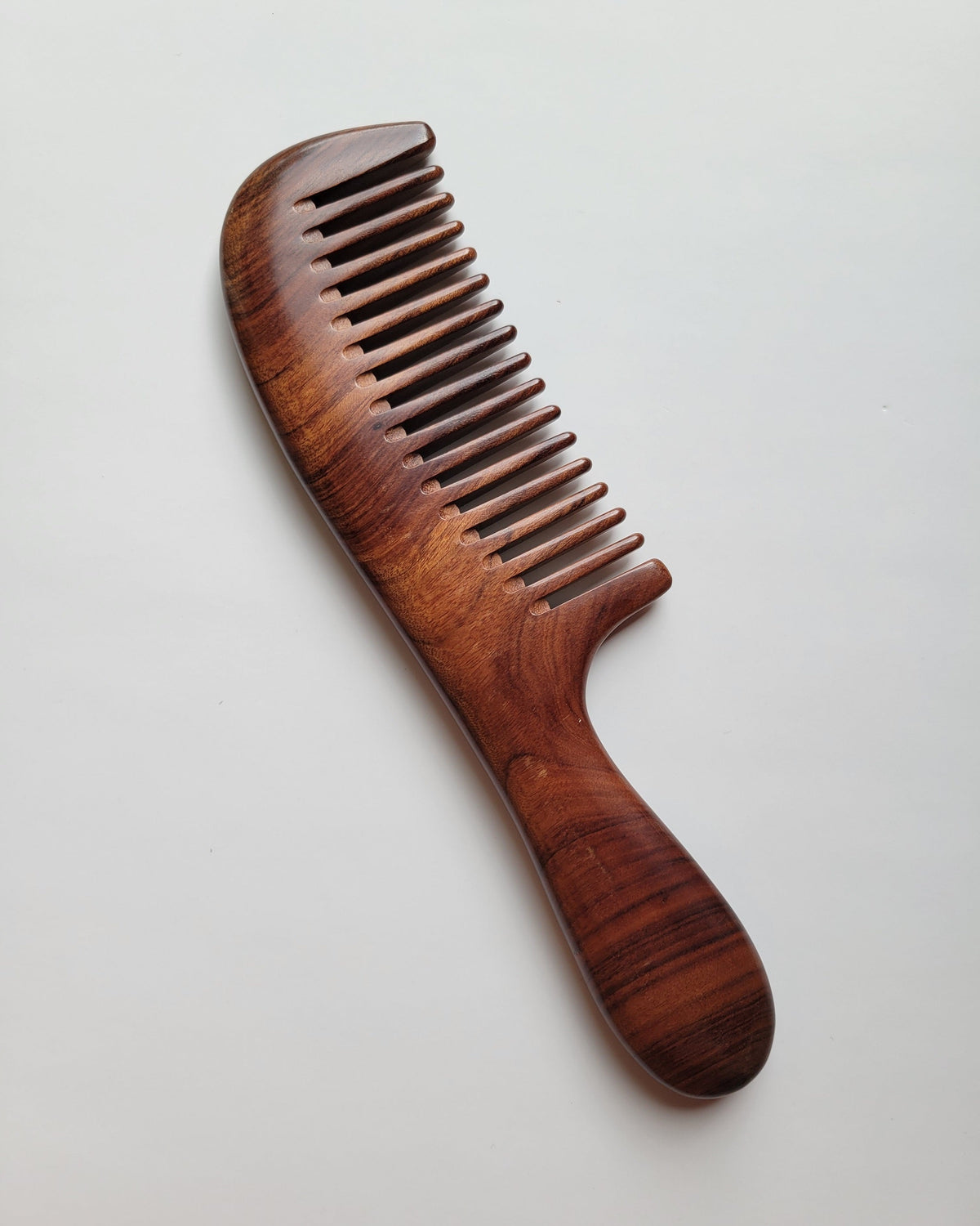 Rich reddish brown Mopane hardwood comb with natural black stripe grain, flat lay overhead view — Arakicrafts