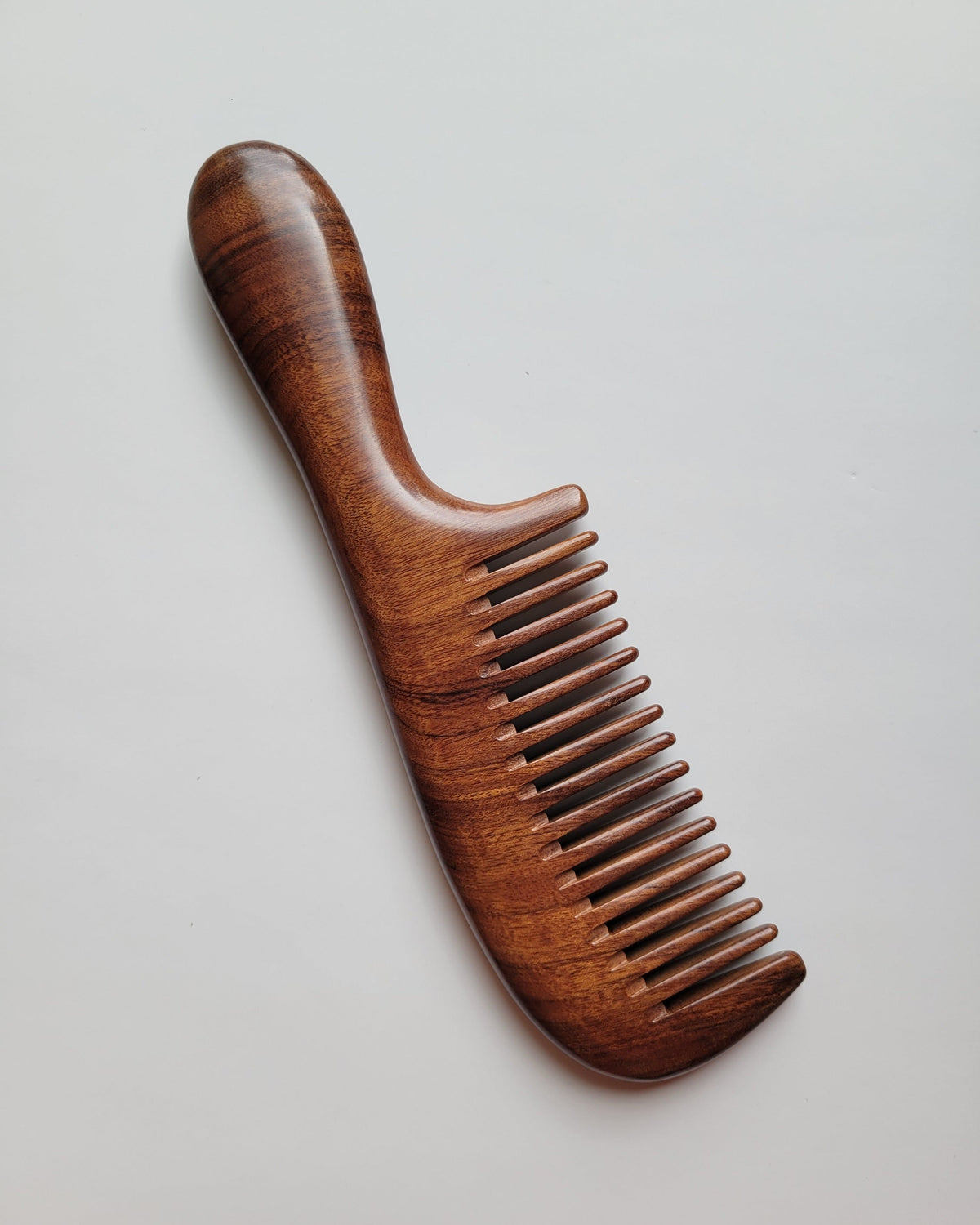 African Mopane wide tooth wood comb with handle, flat lay front view, comes with drawstring gift bag — a luminous gift for her — Arakicrafts