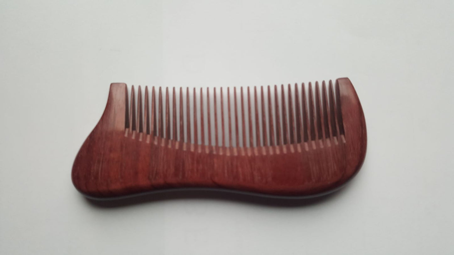 A wooden comb with a curved handle and fine teeth. The comb is made of a reddish-brown wood and has a smooth, polished finish. The teeth are evenly spaced and designed for grooming hair and beard.