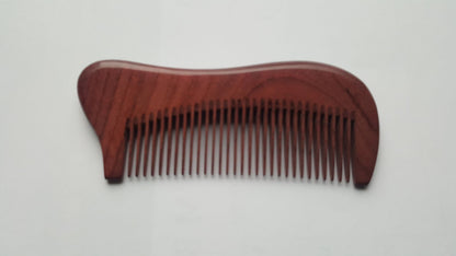 A wooden comb with a curved handle and fine teeth. The comb is made of a reddish-brown wood and has a smooth, polished finish. The teeth are evenly spaced and run the length of the comb-Front view