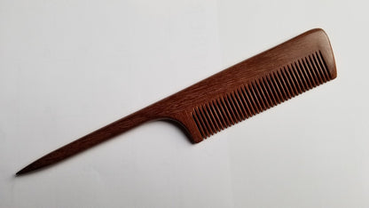 A long, wooden comb with a thin, pointed handle. The comb is made of dark brown wood with a natural grain pattern. Hand inlayed wood comb, sustainable gift