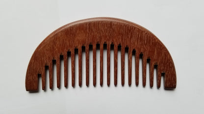 A wooden comb with a curved top and evenly spaced teeth. The comb is made of a reddish-brown wood and has a smooth, polished finish. The teeth are wide and evenly spaced, designed for detangling hair.