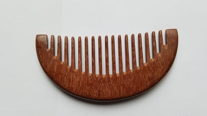 A wooden comb with a curved design. The comb is made of a dark brown pau rosa wood and has evenly spaced teeth. The comb is designed for hair care and grooming - Front view