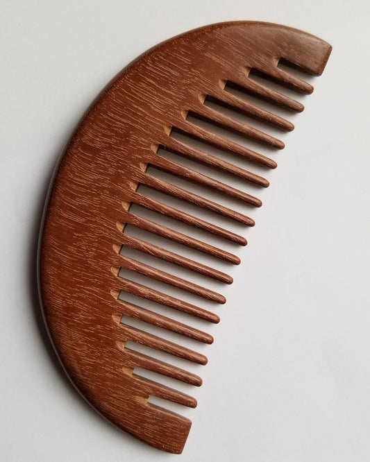A wooden comb with a curved design. The comb is made of a dark brown pau rosa wood and has evenly spaced teeth. The comb is designed for hair care and grooming.  Gift for her and comes with fabric gift bag.