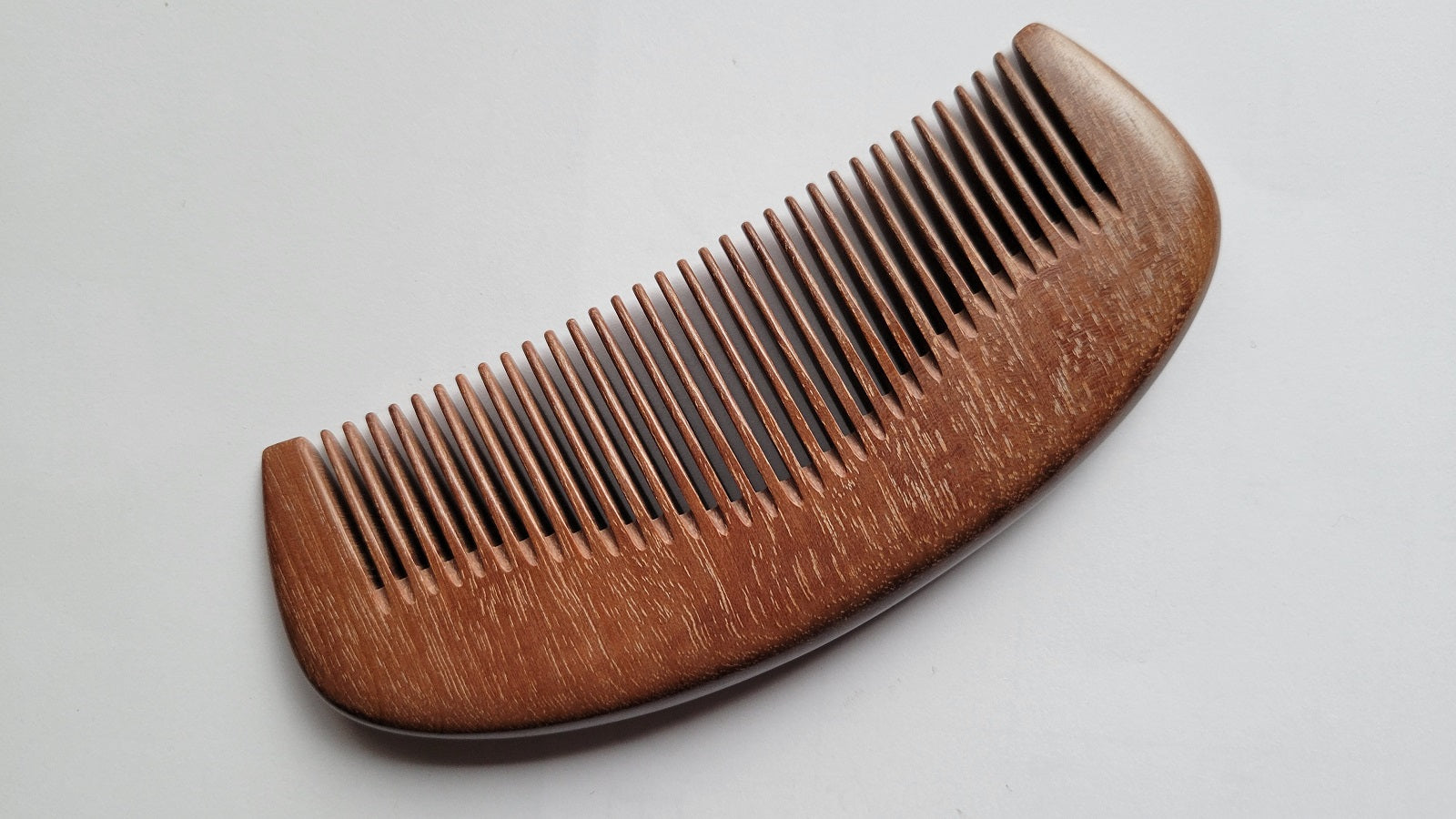 Handcrafted pocket comb with curved silhouette — handle and fine teeth in single-piece Pau Rosa hardwood — Arakicrafts