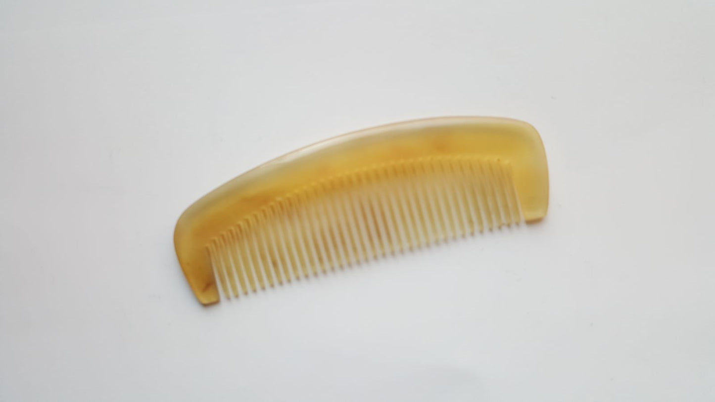  A small sheep horn comb with a curved handle and fine teeth.