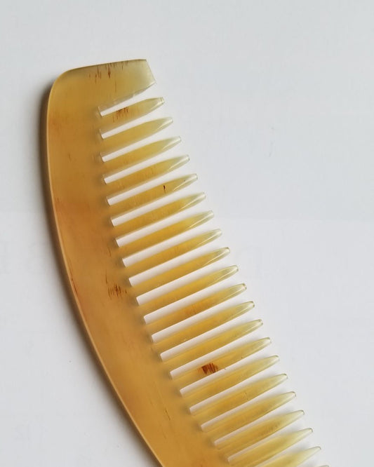 Classic sheep horn wide tooth comb in translucent amber, flat lay front view — natural pale yellow to golden honey tone variation — Arakicrafts