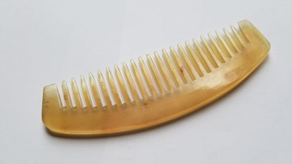 Smooth curved spine of natural sheep horn wide tooth comb, flat lay overhead showing warm translucency and horn grain — Arakicrafts