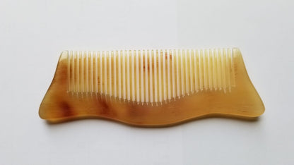 Handmade sheep horn comb with smooth pointed corners on the handle section.