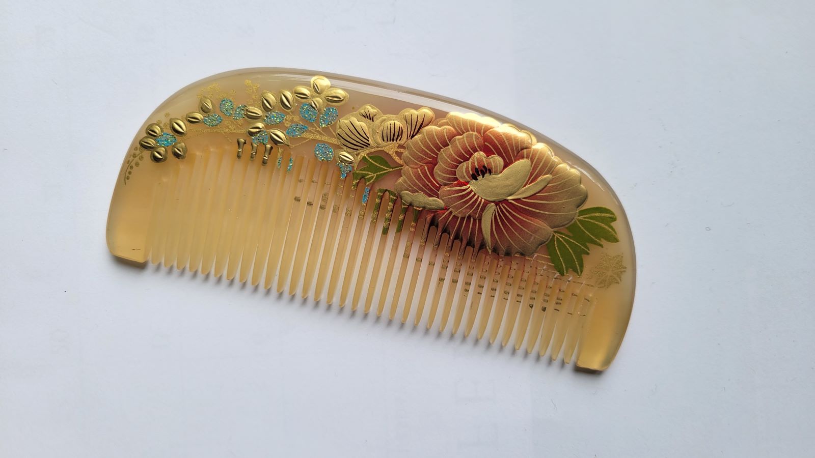 Sheep horn fine tooth comb back view, warm amber translucency, hand-painted peony lacquer art, single-piece natural horn construction