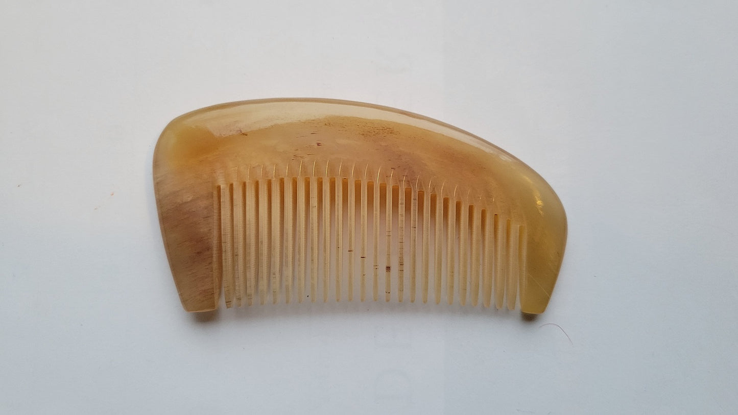 Thick natural sheep horn comb angled view, translucent amber horn body, smooth rounded spine for scalp and neck massage