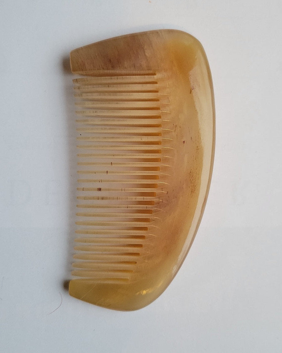 Thick natural sheep horn comb angled view, translucent amber horn body, smooth rounded spine for scalp and neck massage