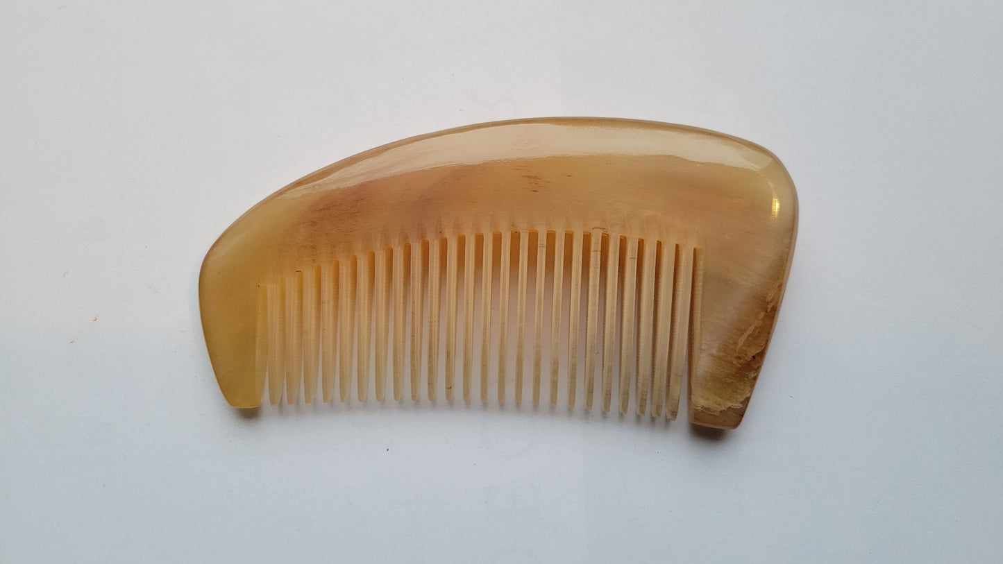 Sheep horn fine tooth comb angled view, warm honey-amber grain, extra-thick crescent body, anti-static natural horn hair comb
