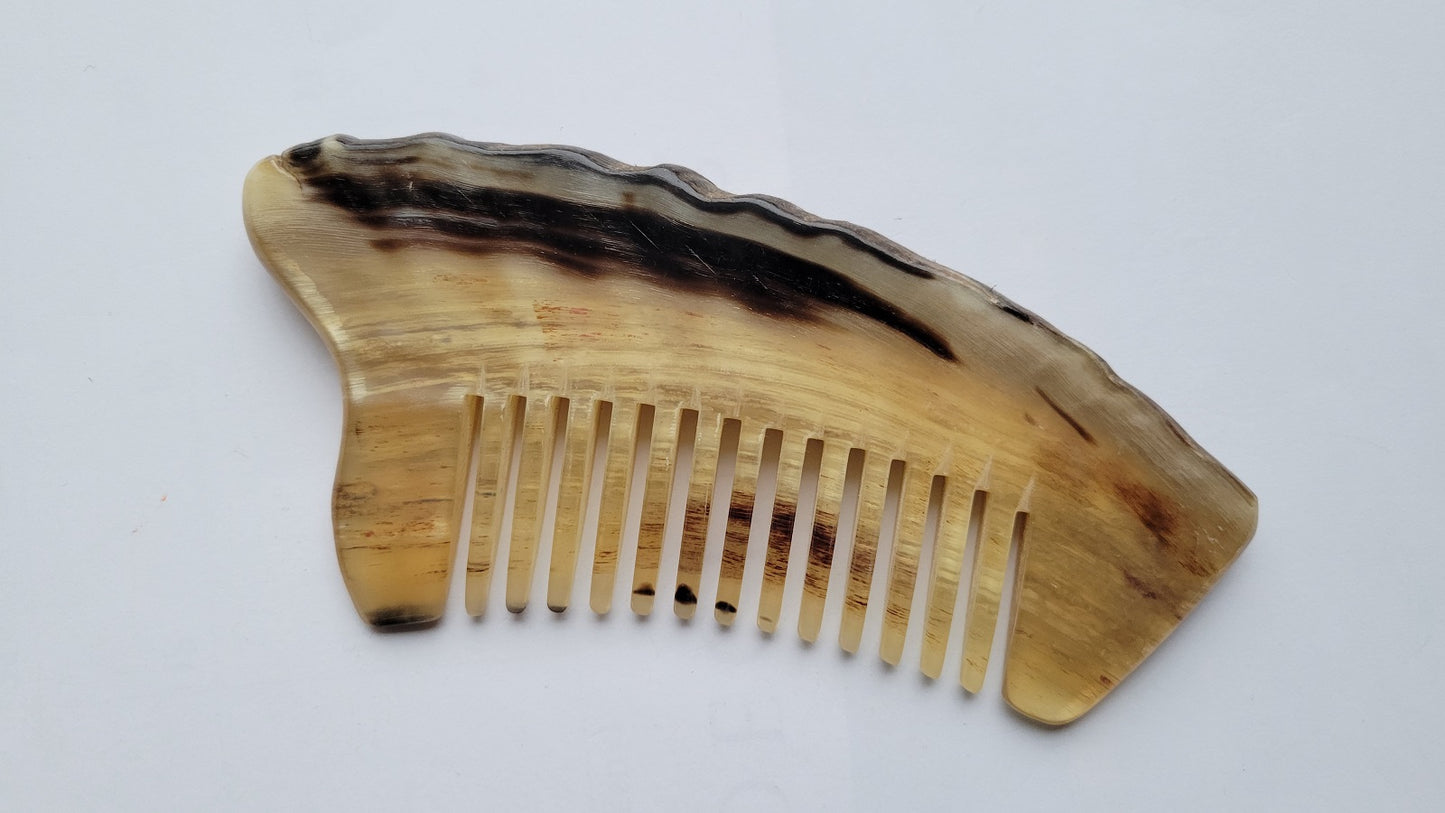 Handcrafted wide-tooth comb — flat lay angled to show natural horn grain and color variation
