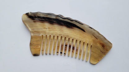 Handcrafted wide-tooth comb — flat lay angled to show natural horn grain and color variation