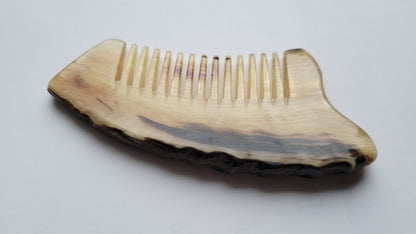 rustic sheep horn comb with wide tooth and unrefined curved edge. 