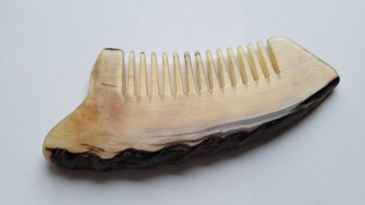 rustic sheep horn comb with wide tooth and unrefined curved edge.  