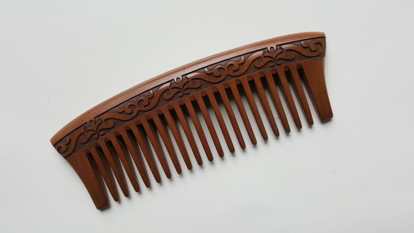 A brown peach wood wooden comb with a carved harakusa design. The comb is anti static and can help to control frizz. 