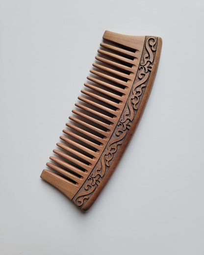 A brown peach wood wooden comb with a carved harakusa design. The comb is anti static and can help to control frizz. 