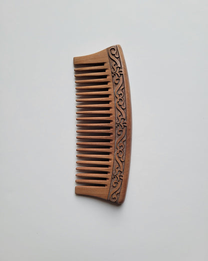vintage style peach wood wooden comb with a carved karakusa design. The comb has evenly spaced wide teeth and can massage the scalp while you comb the hair daily. 