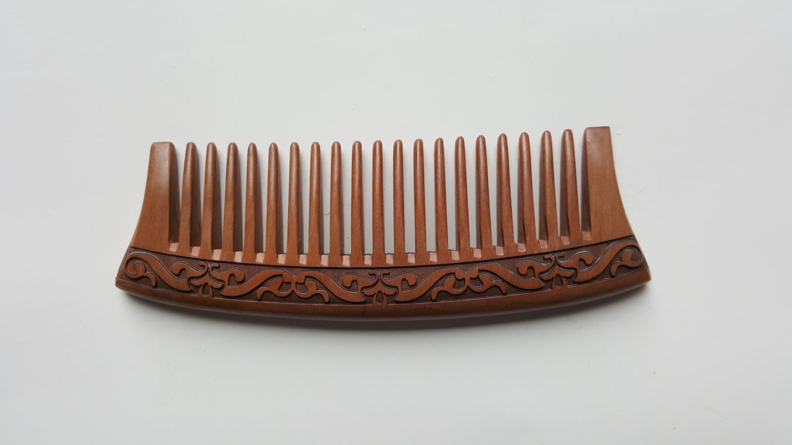 This peach wood comb has a curved shape and wide tooth. it is designed for hair and beard grooming. comes with carrying case. 