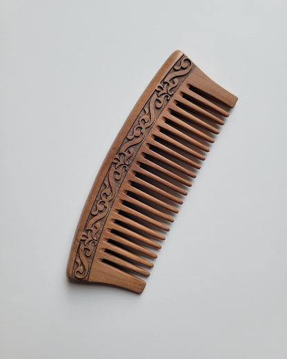 This peach wood comb has a curved shape and wide tooth. it is designed for hair and beard grooming. comes with carrying case. 