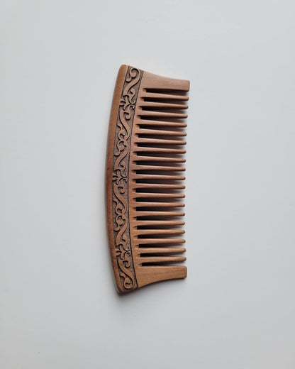 Handmade brown peach wood comb with a carved karakusa design. The comb is good for daily natural hair grooming