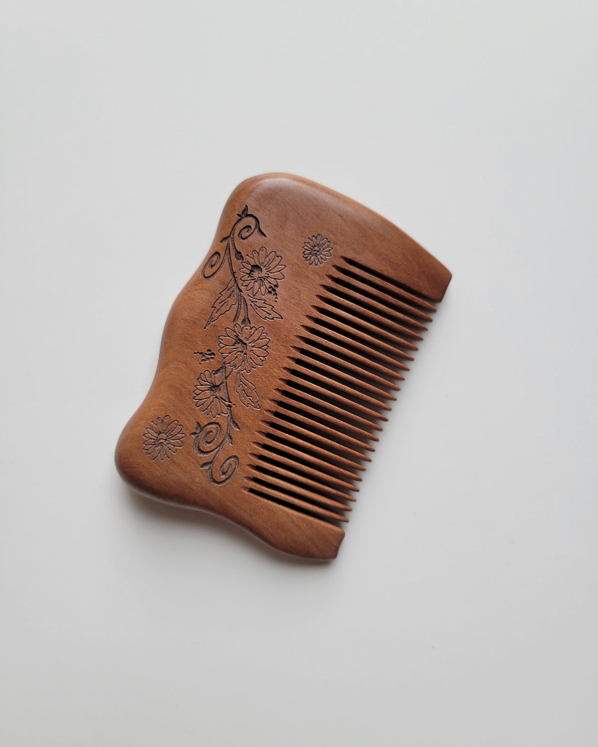 Compact anti-static wooden comb with a contoured grip and smooth brown finish, shown at an angle with teeth pointing right. comes with a carrying bag and ready to gift