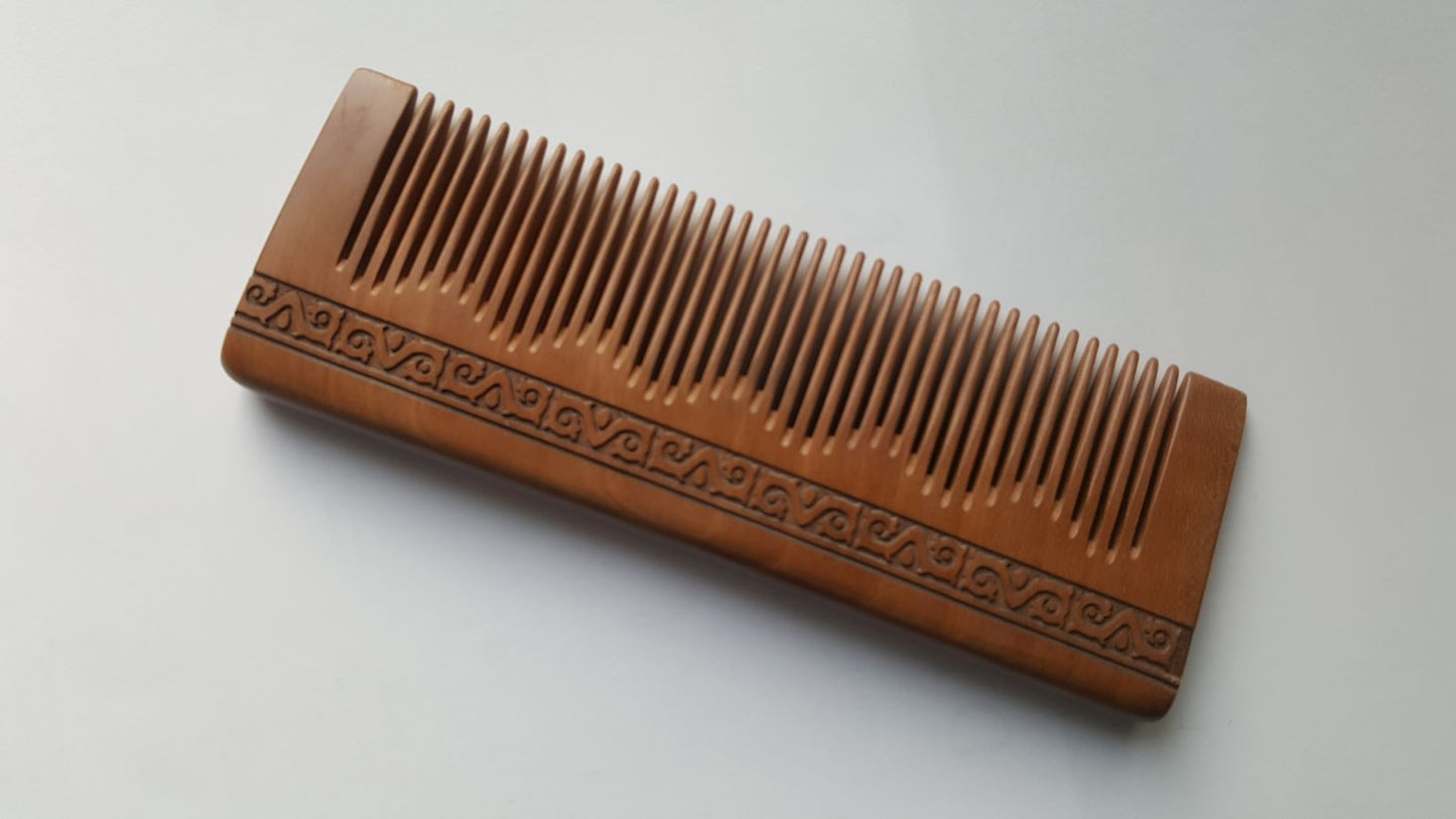 Meandros peach wood comb with hand-carved Greek meander spiral pattern, warm pinkish-brown grain

