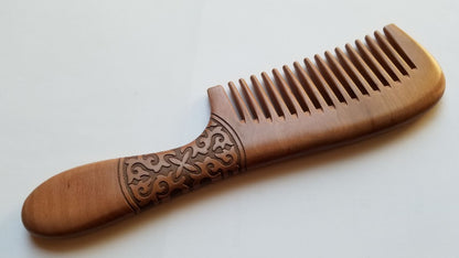 Close-up of swirling spiral vine carving on peach wood comb handle — hand carved artisan detail — Arakicrafts